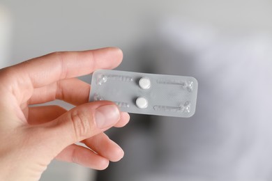 Photo of Woman holding blister of emergency contraception pills on white background, closeup