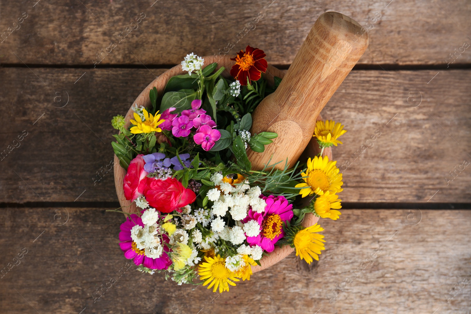 Photo of Mortar, pestle and different flowers on wooden table, top view