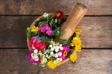 Photo of Mortar, pestle and different flowers on wooden table, top view