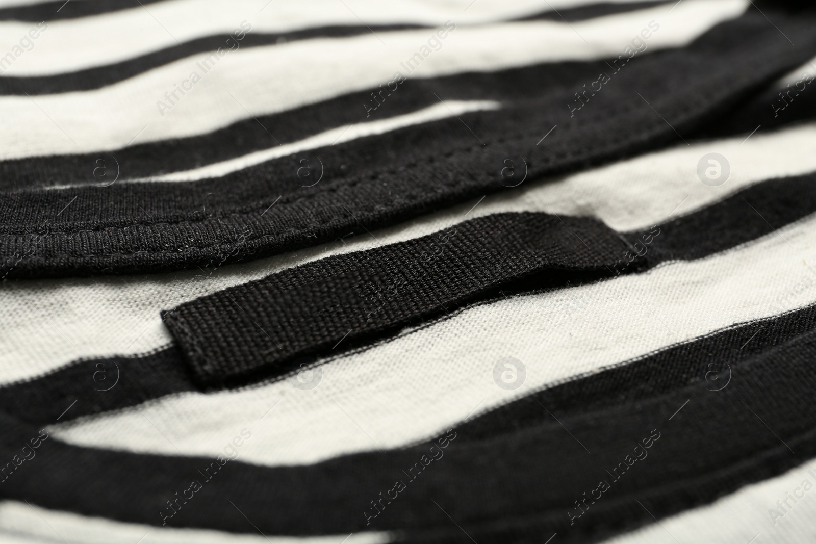 Photo of Blank clothing label on striped T-shirt, closeup