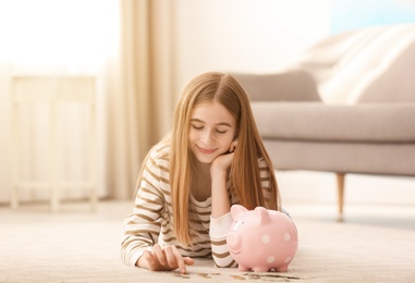 Photo of Teen girl with piggy bank and money at home