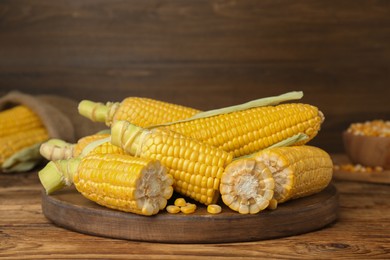 Photo of Fresh corncobs on wooden table. Space for text