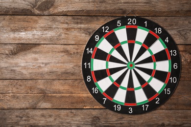 Dart board on wooden background, top view. Space for text