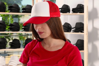 Photo of Young woman in blank colorful cap at store. Mock up for design