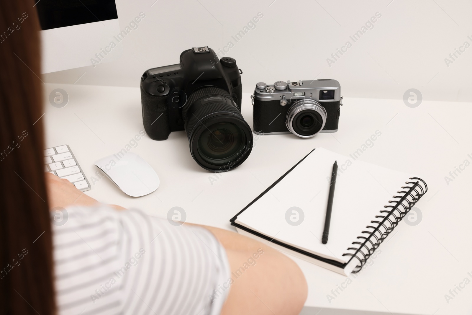 Photo of Photographer working at white table with cameras indoors, closeup