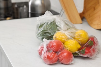 Plastic bags with different fresh products on white countertop in kitchen. Space for text