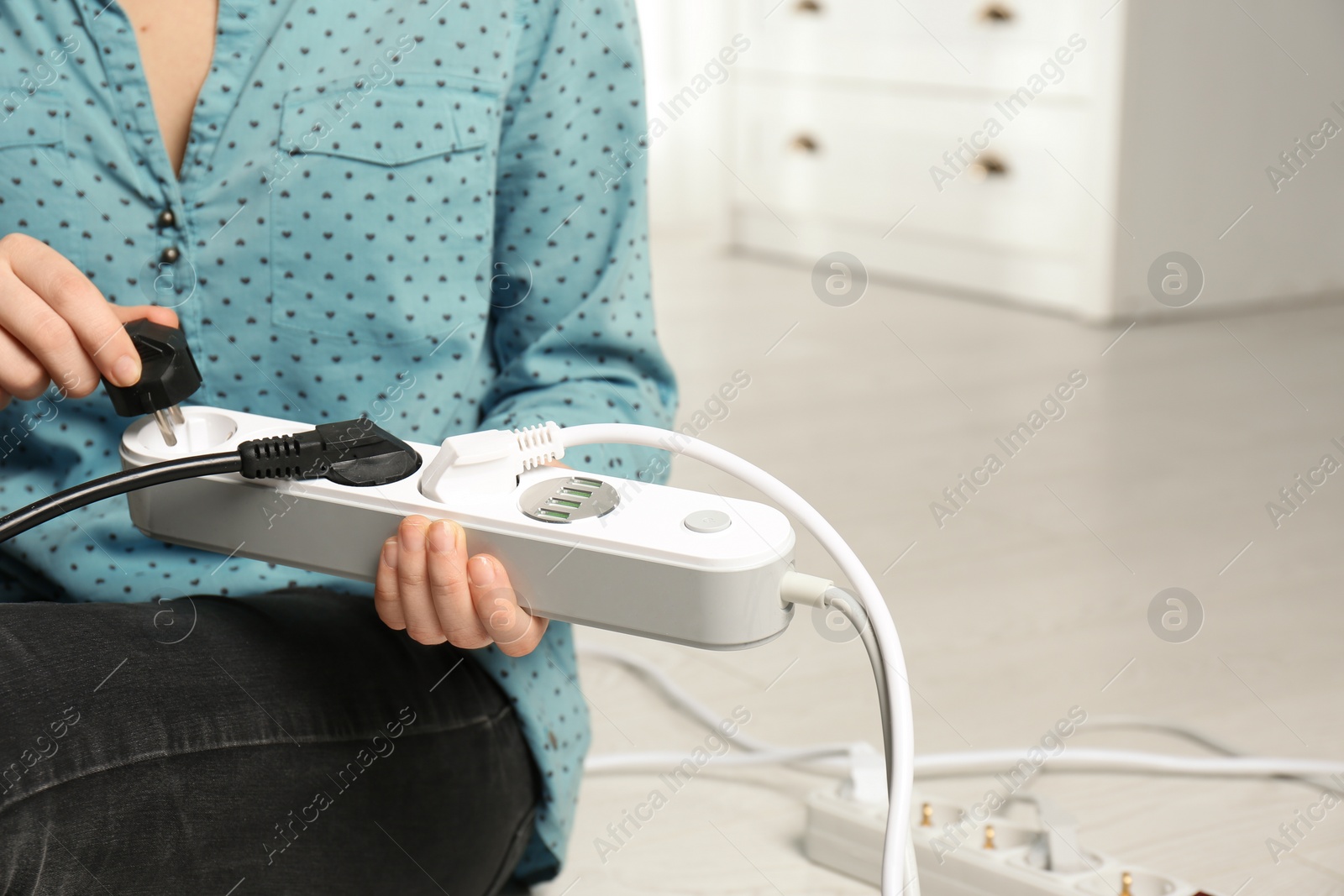 Photo of Woman inserting power plug into extension cord indoors, closeup with space for text. Electrician's professional equipment