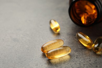 Dietary supplement capsules on grey table, closeup. Space for text