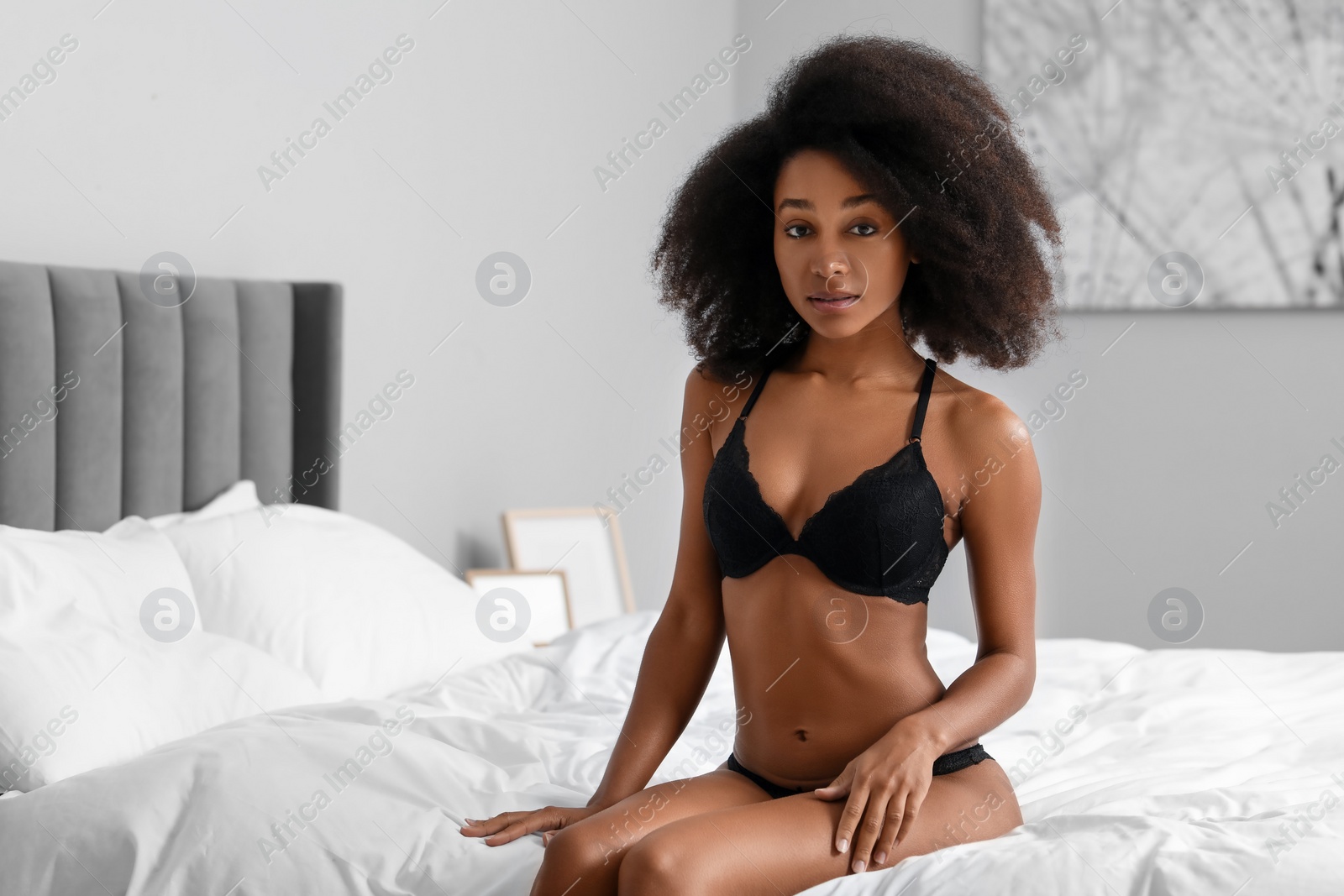 Photo of Beautiful woman in elegant black underwear on bed indoors, space for text