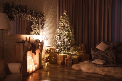 Stylish interior with beautiful Christmas tree and artificial fireplace at night