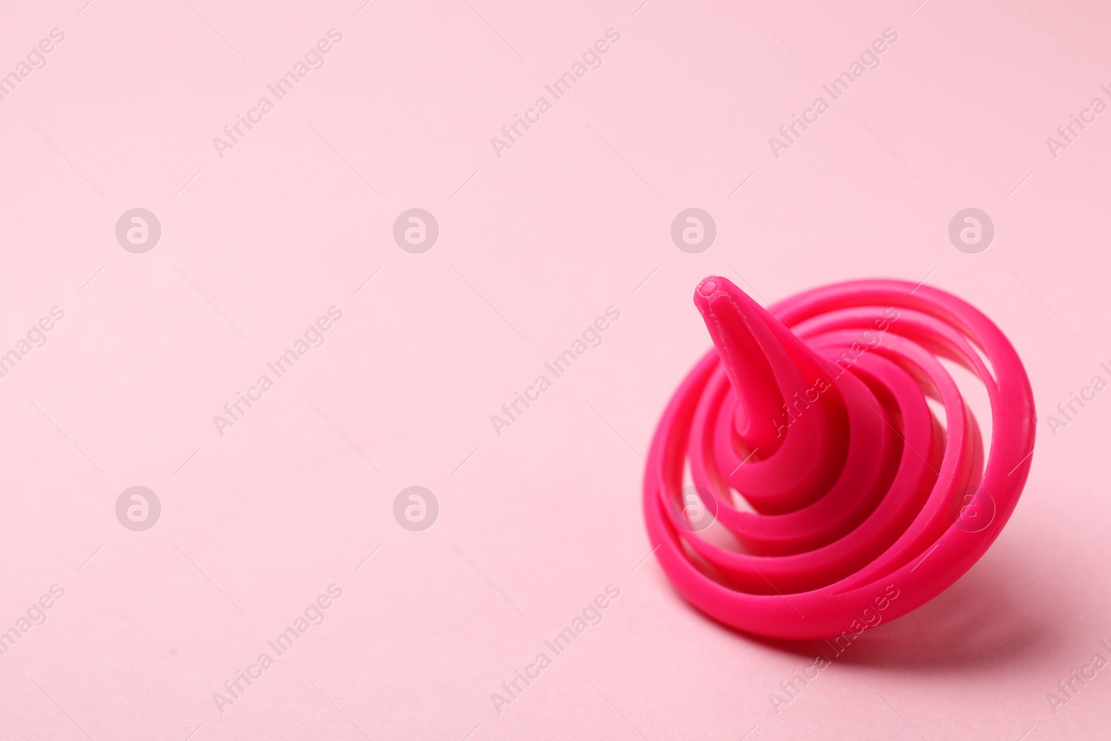 Photo of One spinning top on pink background, closeup. Space for text