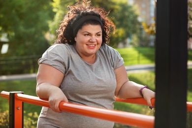 Beautiful overweight woman training on sports ground