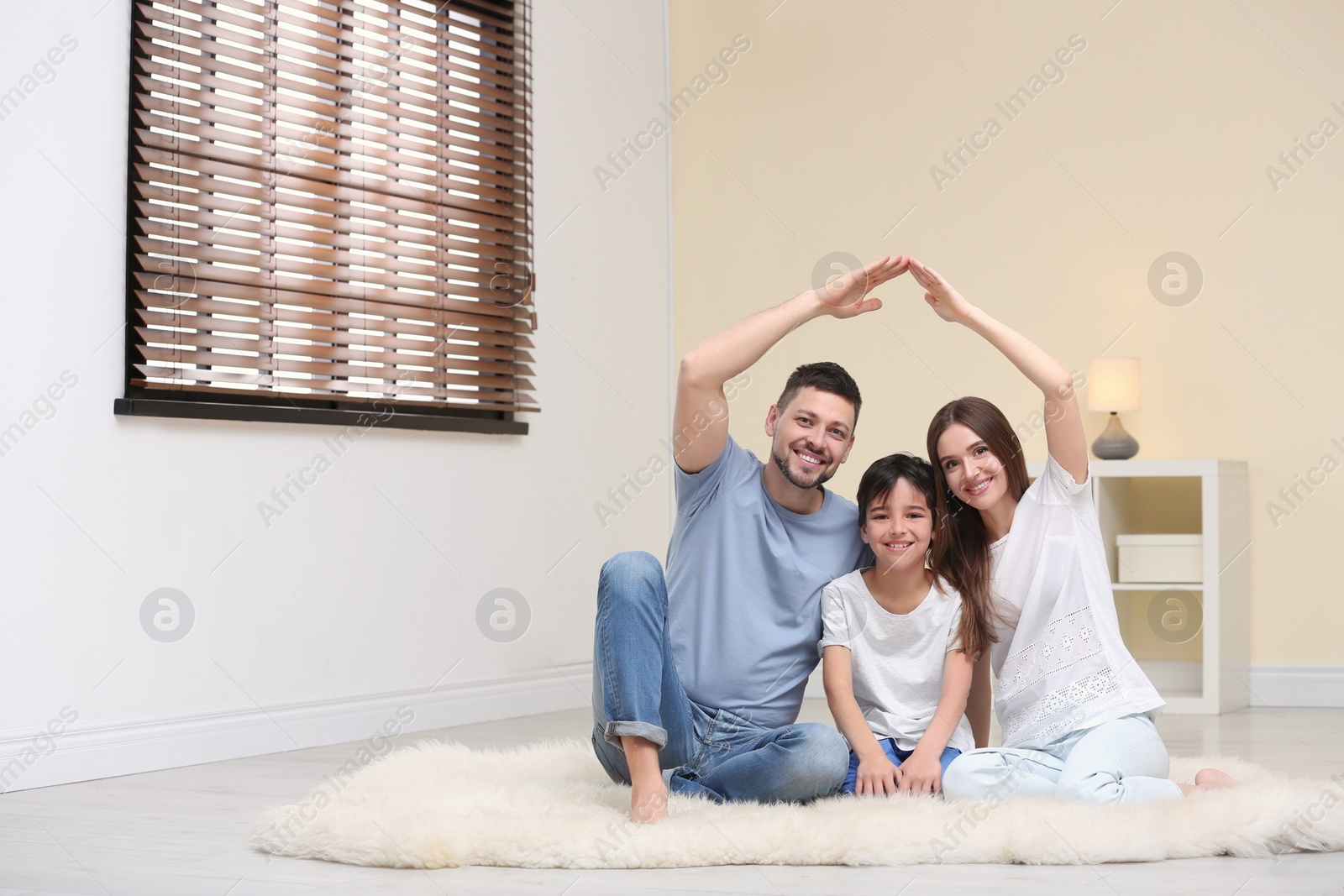 Photo of Happy family forming house roof with their hands at home. Insurance concept