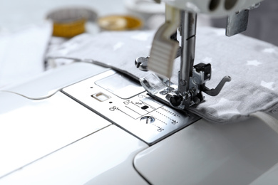 Photo of Sewing machine with homemade protective mask, closeup