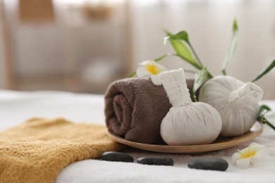 Photo of Spa stones, flowers and herbal bags on towel indoors, closeup