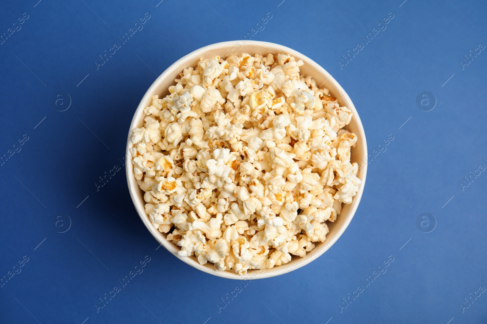 Photo of Tasty pop corn on blue background, top view