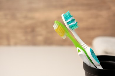 Toothbrushes in holder on blurred background, closeup. Space for text