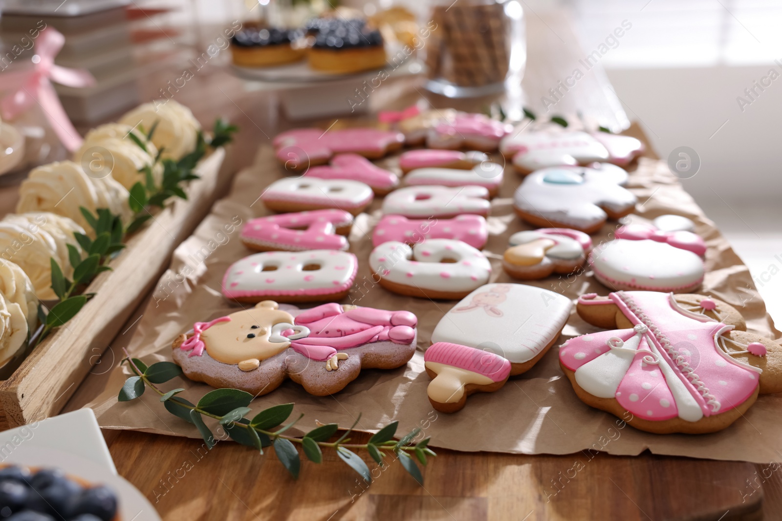 Photo of Baby shower party. Delicious cookies on wooden table indoors, closeup
