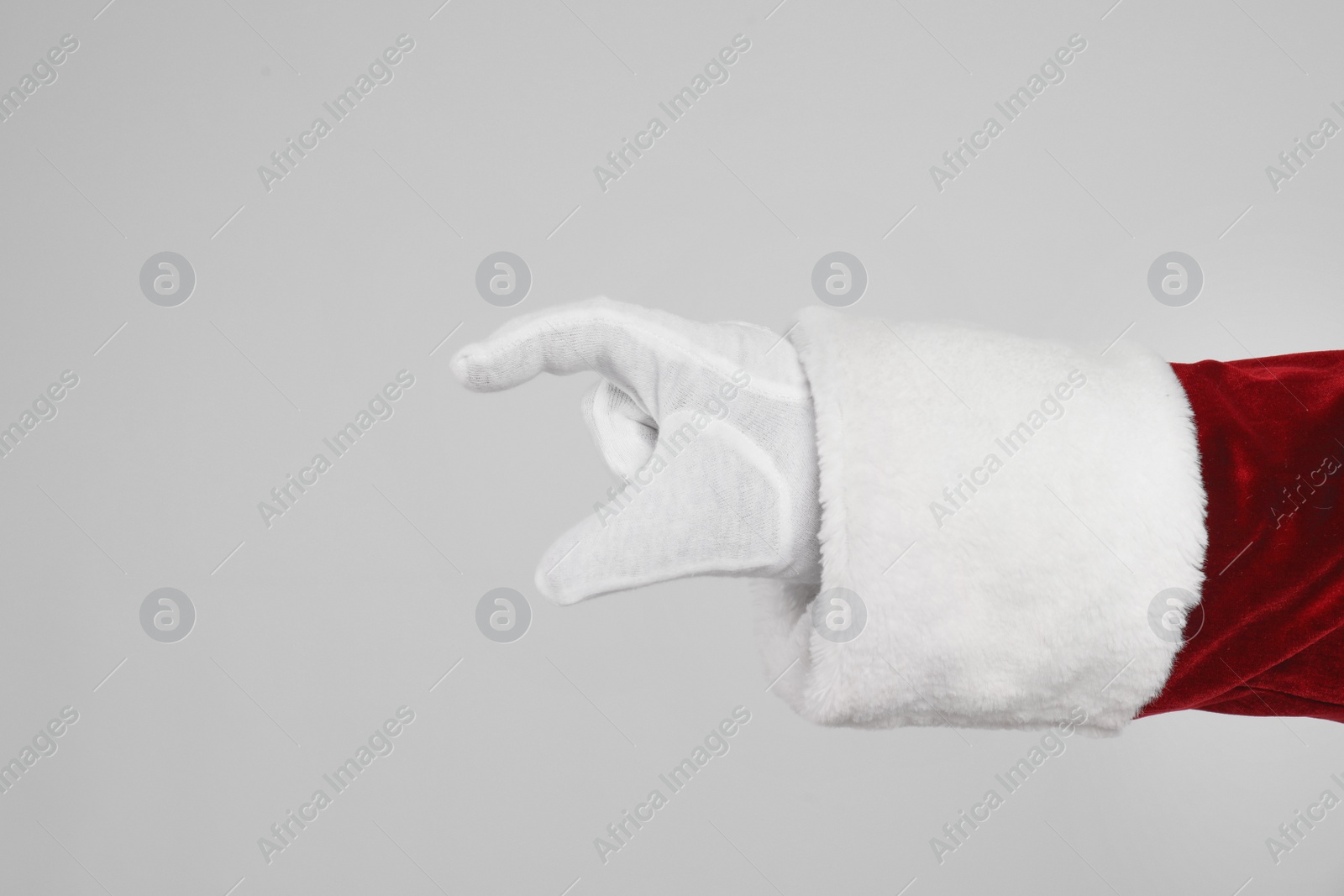 Photo of Santa Claus holding something on light grey background, closeup of hand