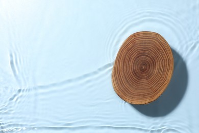 Photo of Presentation of product. Wooden podium in water on light blue background, top view. Space for text