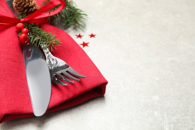 Photo of Cutlery set and Christmas decor on light grey table, closeup. Space for text