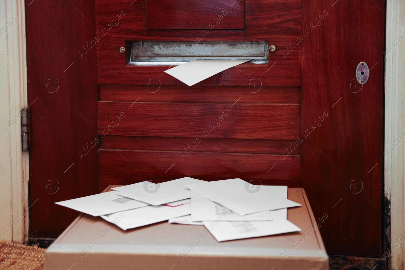 Photo of Wooden door with mail slot, many envelopes and cardboard indoors