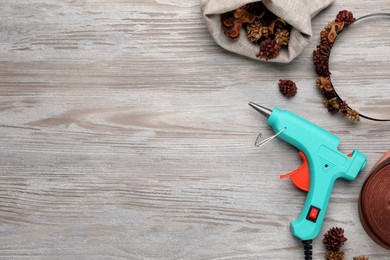 Photo of Hot glue gun, decorated headband and handicraft materials on wooden table, flat lay. Space for text