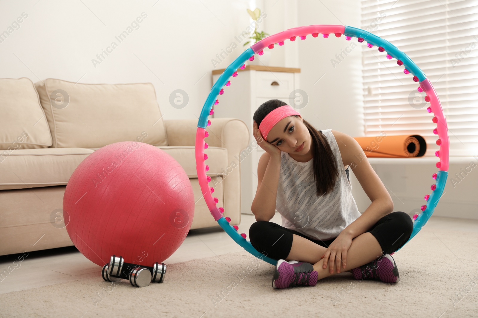 Photo of Lazy young woman with sport equipment at home