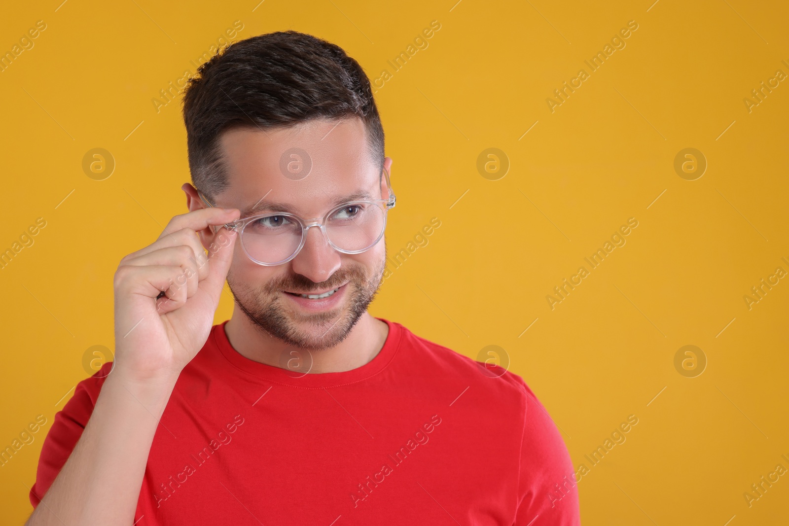 Photo of Portrait of happy man in stylish glasses on yellow background. Space for text