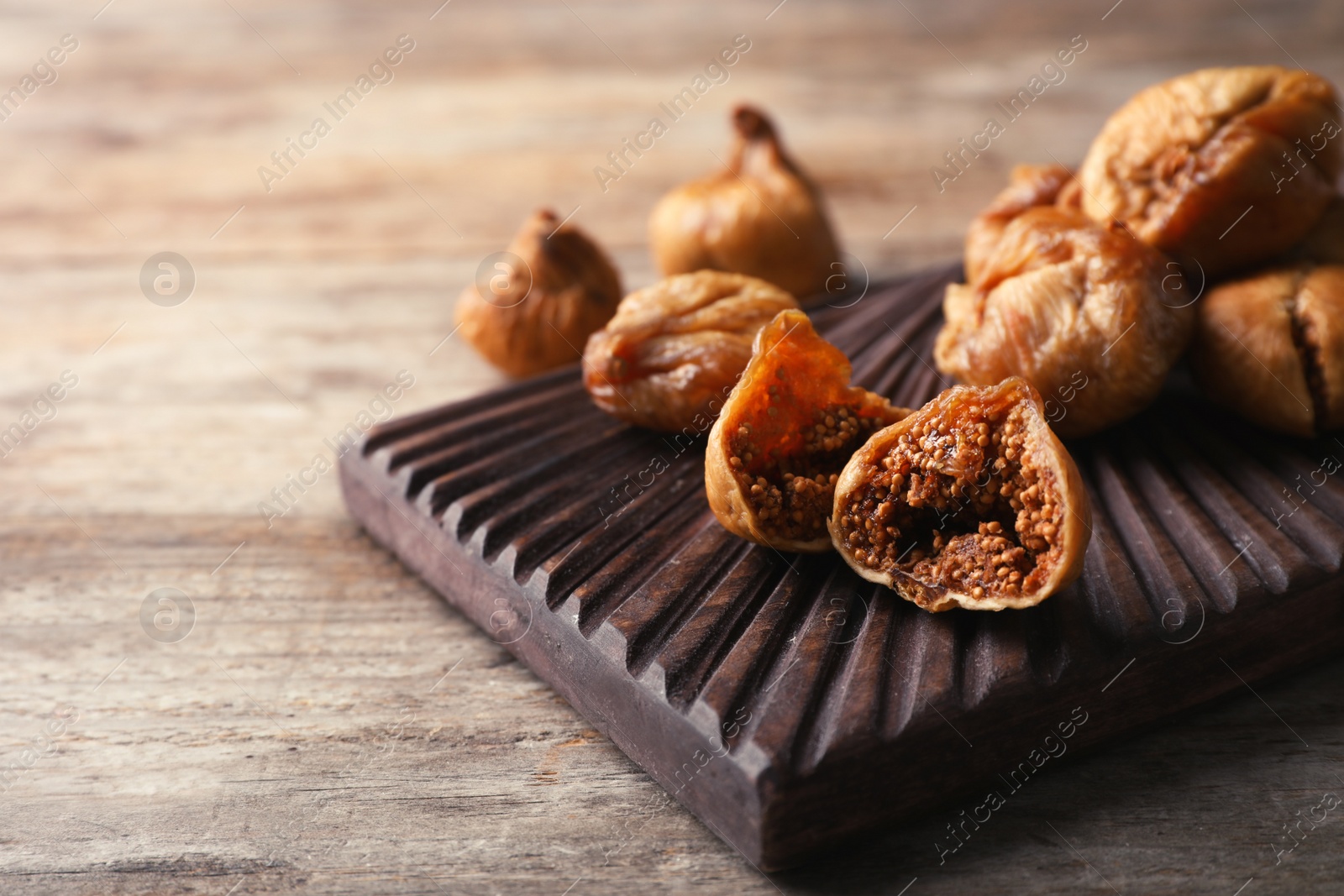 Photo of Board with dried figs on wooden table. Organic snack