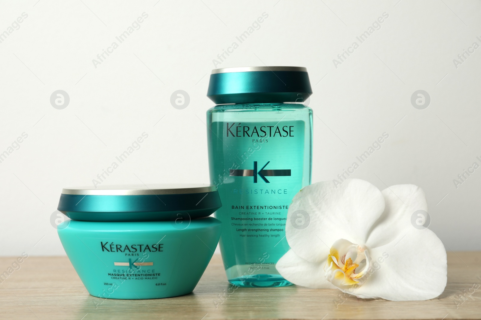 Photo of MYKOLAIV, UKRAINE - SEPTEMBER 07, 2021: Kerastase hair care cosmetic products and beautiful orchid flower on wooden table