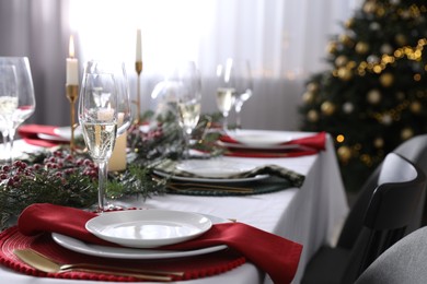 Photo of Christmas table setting with festive decor and dishware indoors