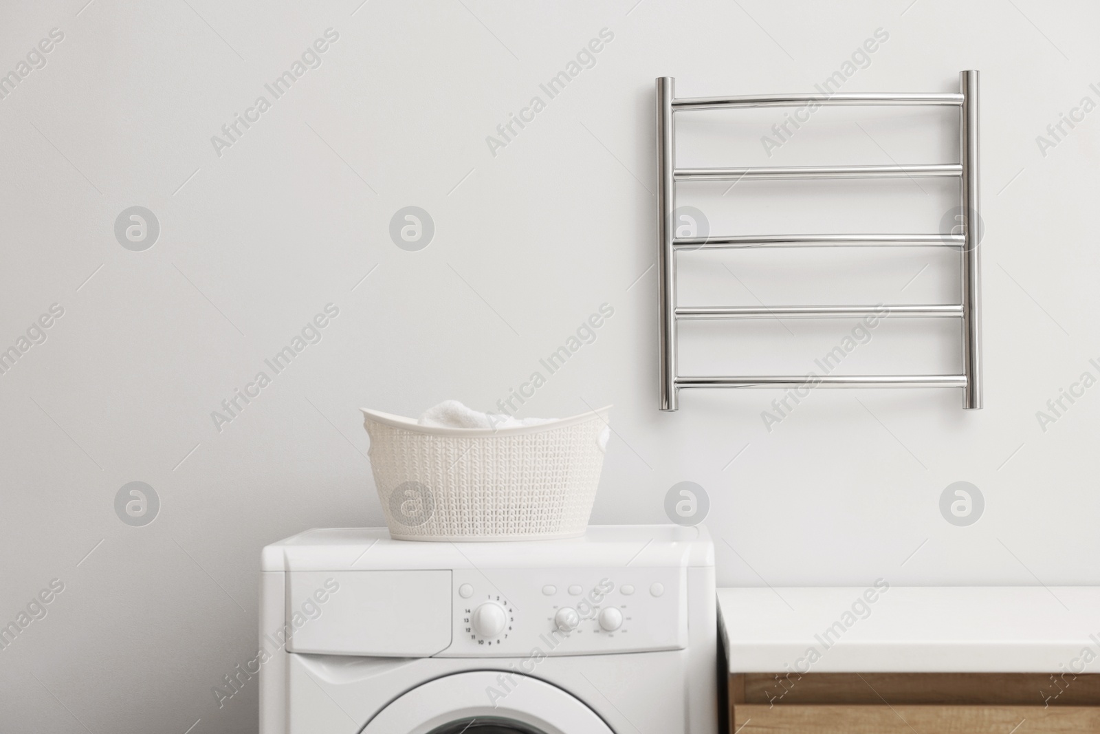 Photo of Stylish bathroom interior with heated towel rail and washing machine