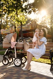 Photo of Happy mother with baby sitting on bench in park