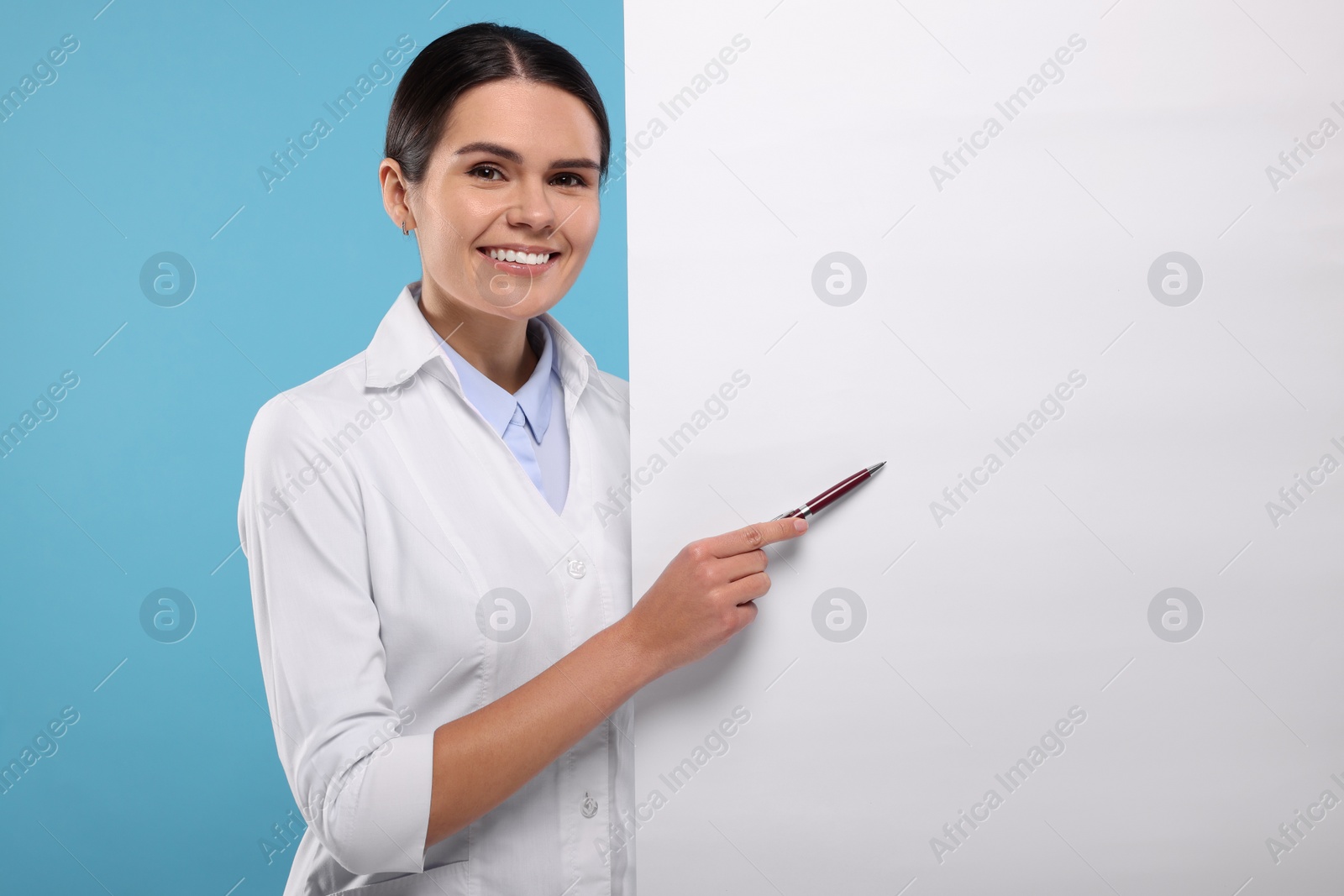 Photo of Ophthalmologist pointing at blank banner on light blue background, space for text