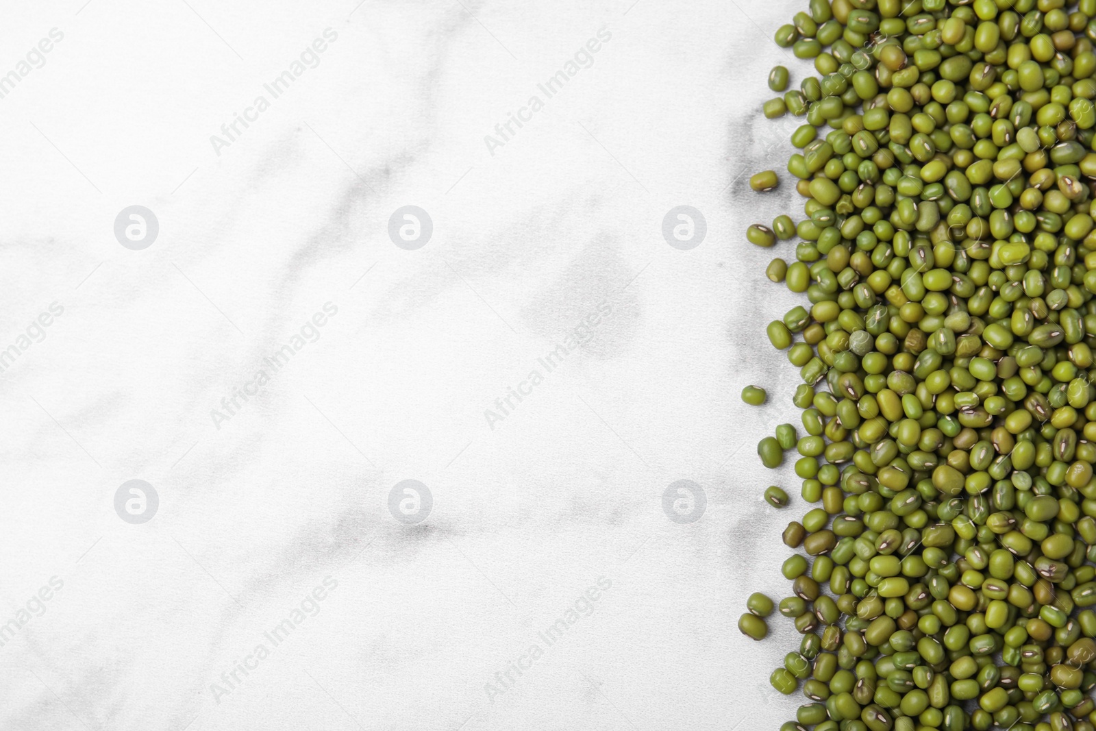 Photo of Green mung beans on white marble table, top view. Space for text