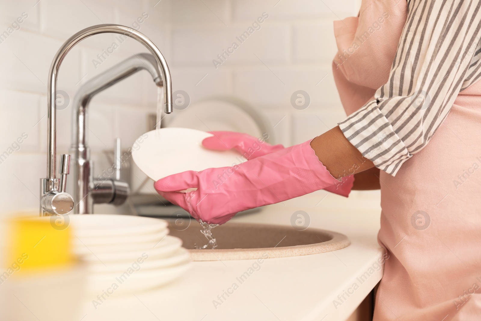 Photo of Woman doing washing up in kitchen sink, closeup view. Cleaning chores