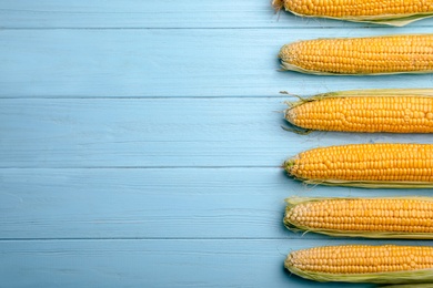 Flat lay composition with tasty sweet corn cobs on wooden background