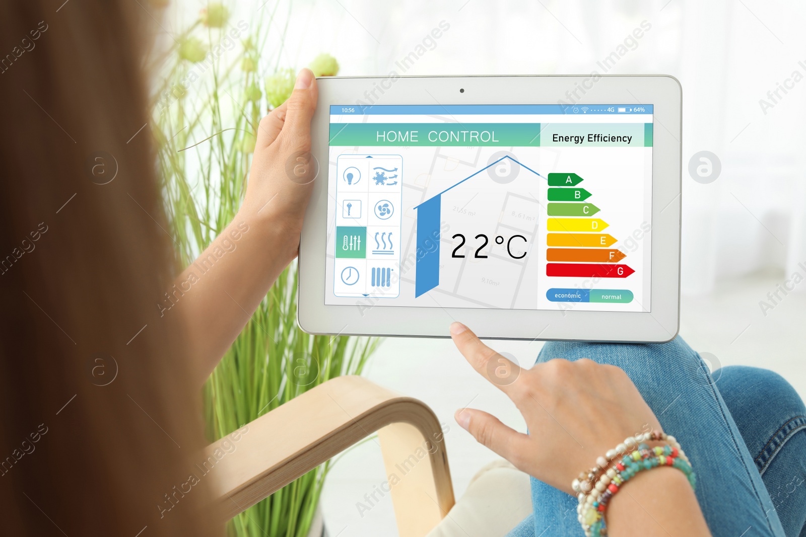 Image of Energy efficiency home control system. Woman using tablet to set indoor temperature, closeup