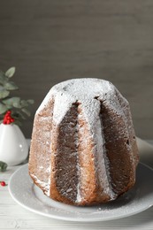 Delicious Pandoro cake decorated with powdered sugar on white wooden table. Traditional Italian pastry