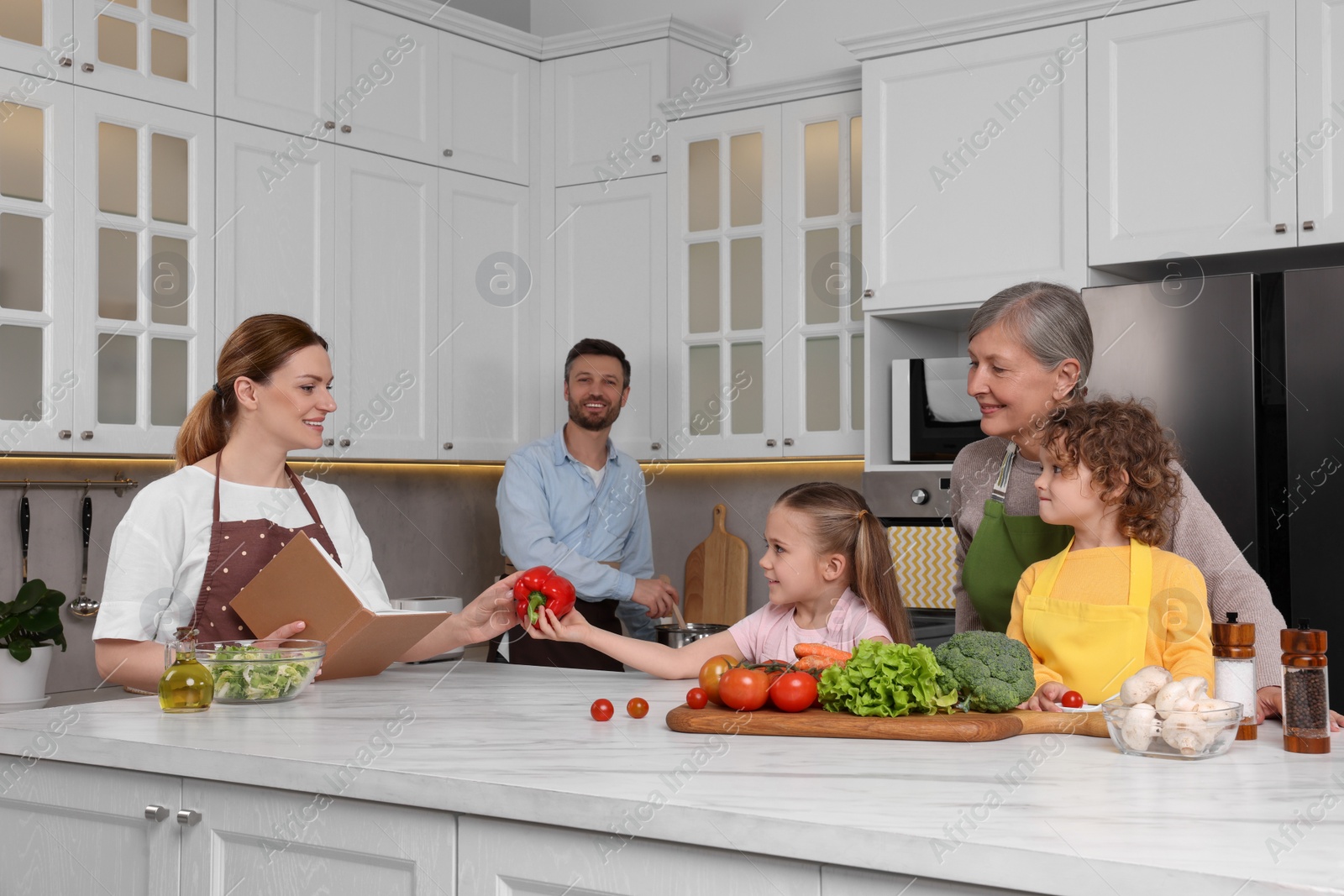 Photo of Family cooking by recipe book in kitchen