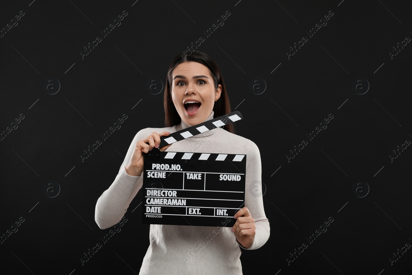 Photo of Emotional actress with clapperboard on black background. Film industry