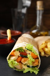 Photo of Delicious chicken shawarma on slate plate, closeup