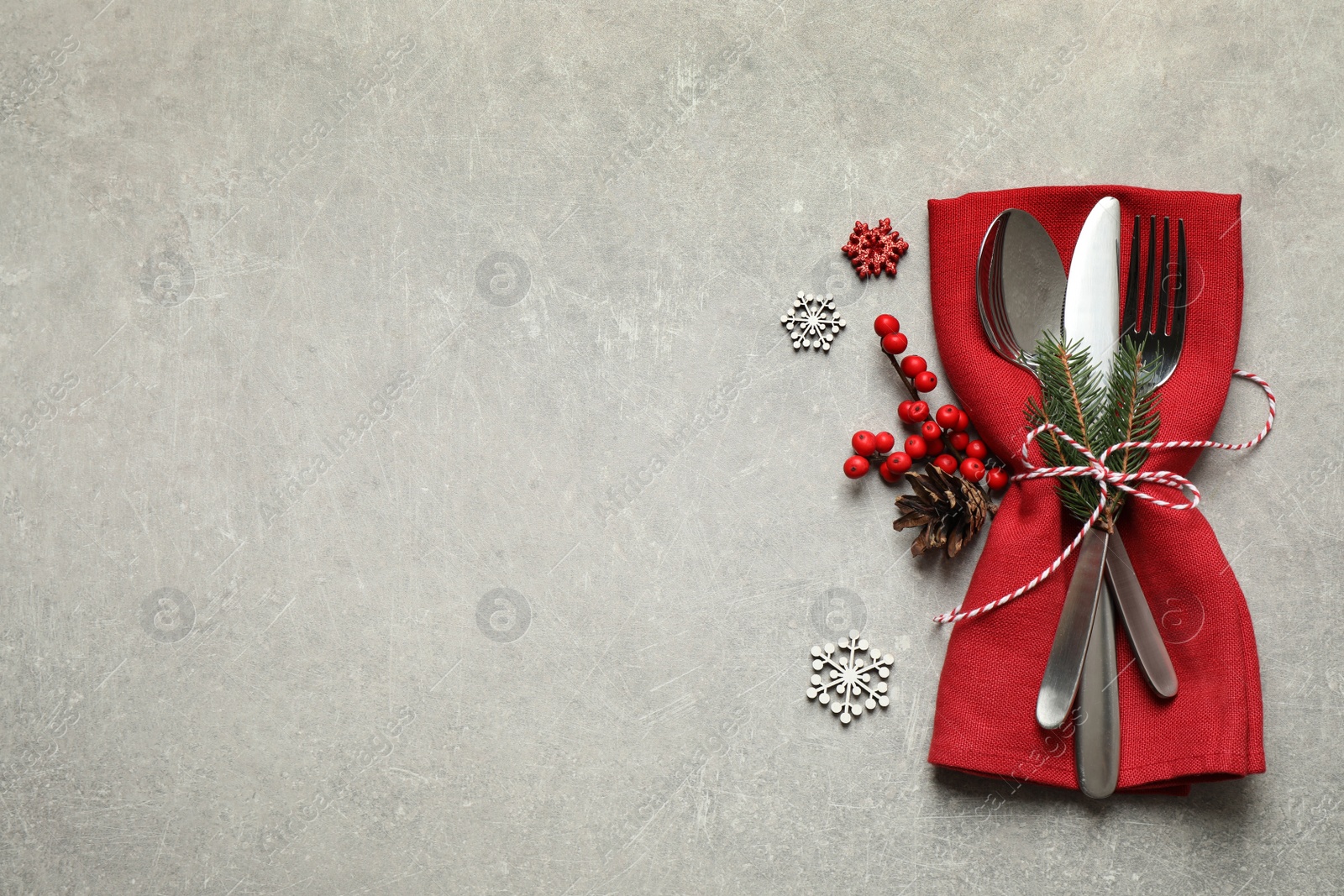 Photo of Cutlery set and festive decor on light grey table, flat lay with space for text. Christmas celebration