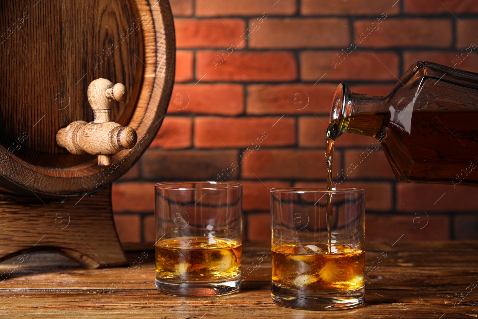 Photo of Pouring whiskey from bottle into glass on wooden table