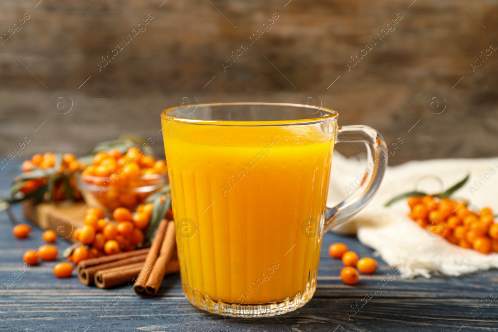 Photo of Fresh sea buckthorn tea on blue wooden table