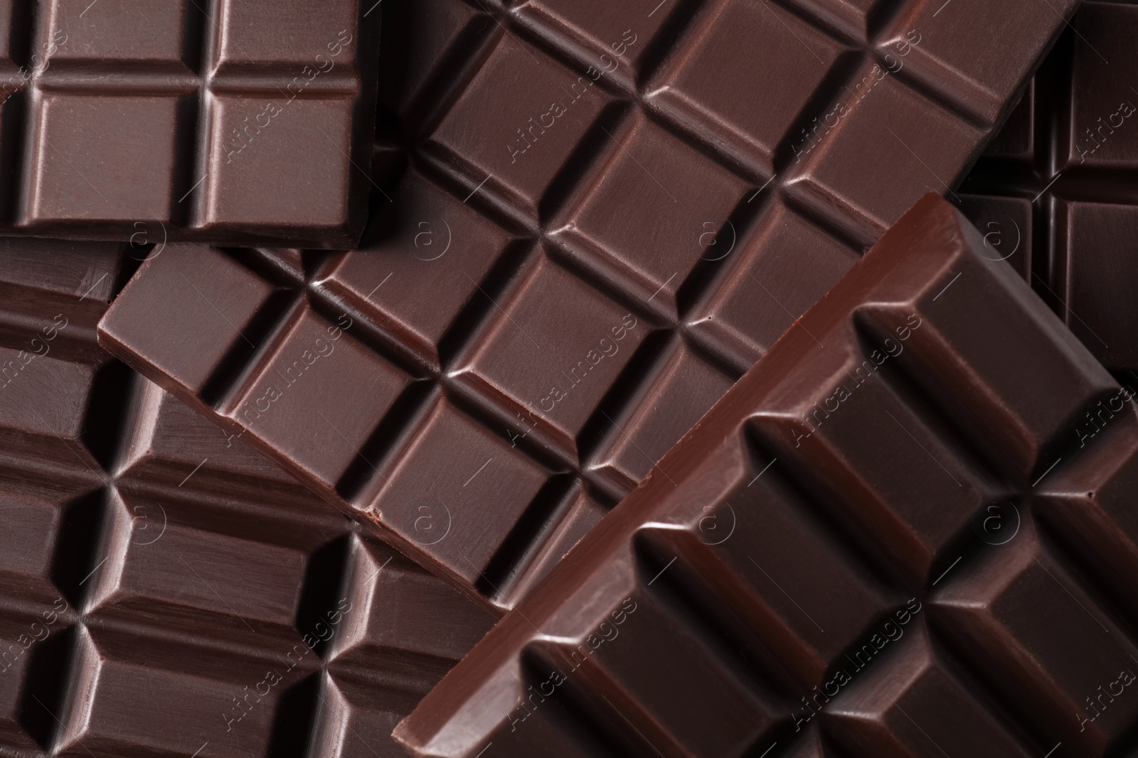 Photo of Many delicious dark chocolate bars as background, top view