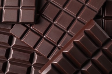 Photo of Many delicious dark chocolate bars as background, top view