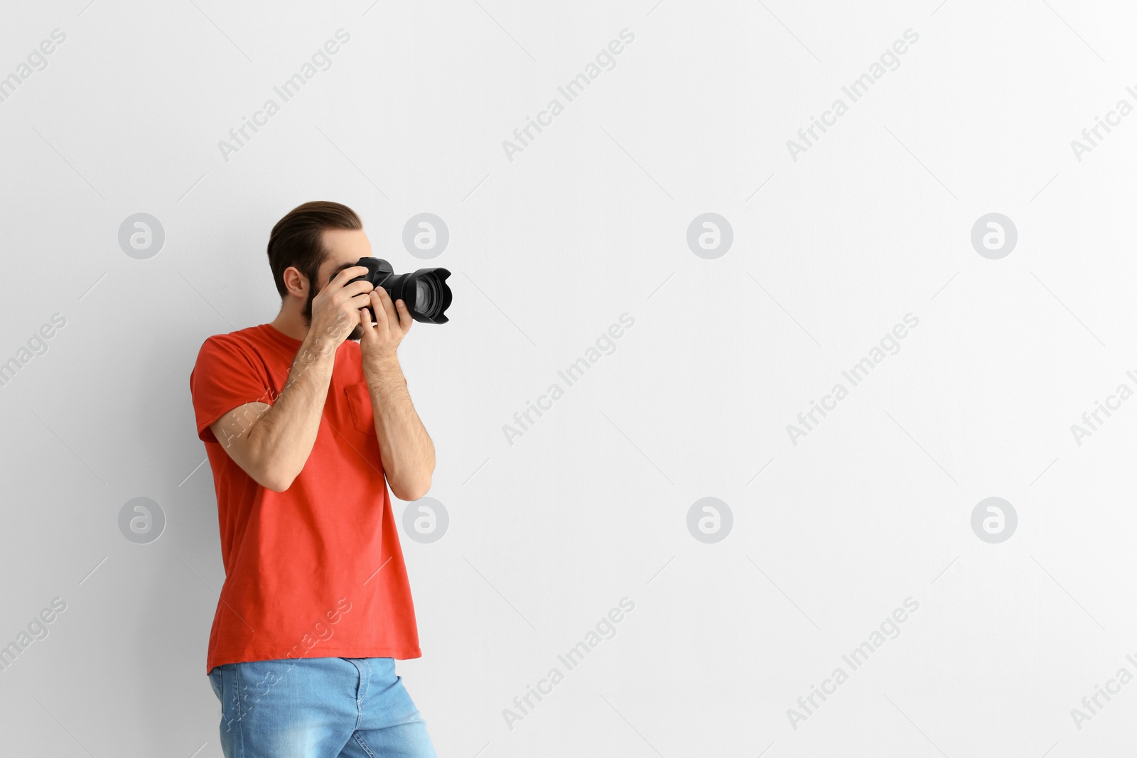 Photo of Young photographer with professional camera on white background