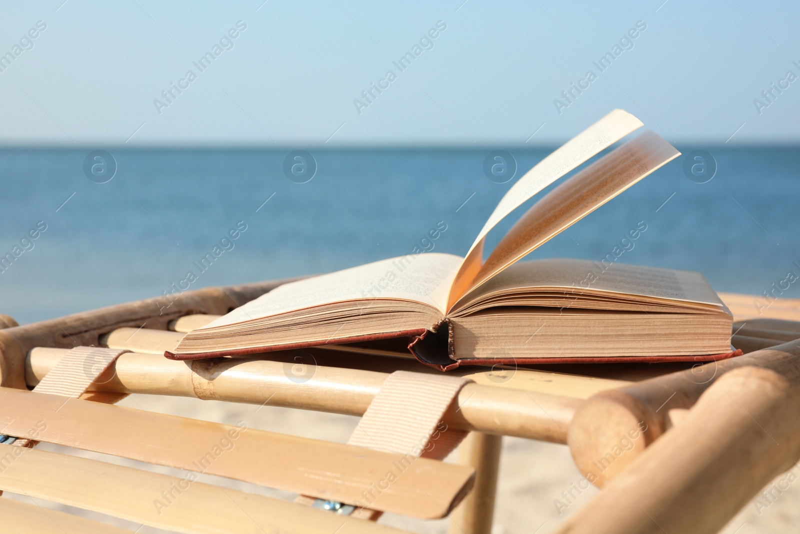 Photo of Book on wooden deck chair at seaside. Reading while vacation